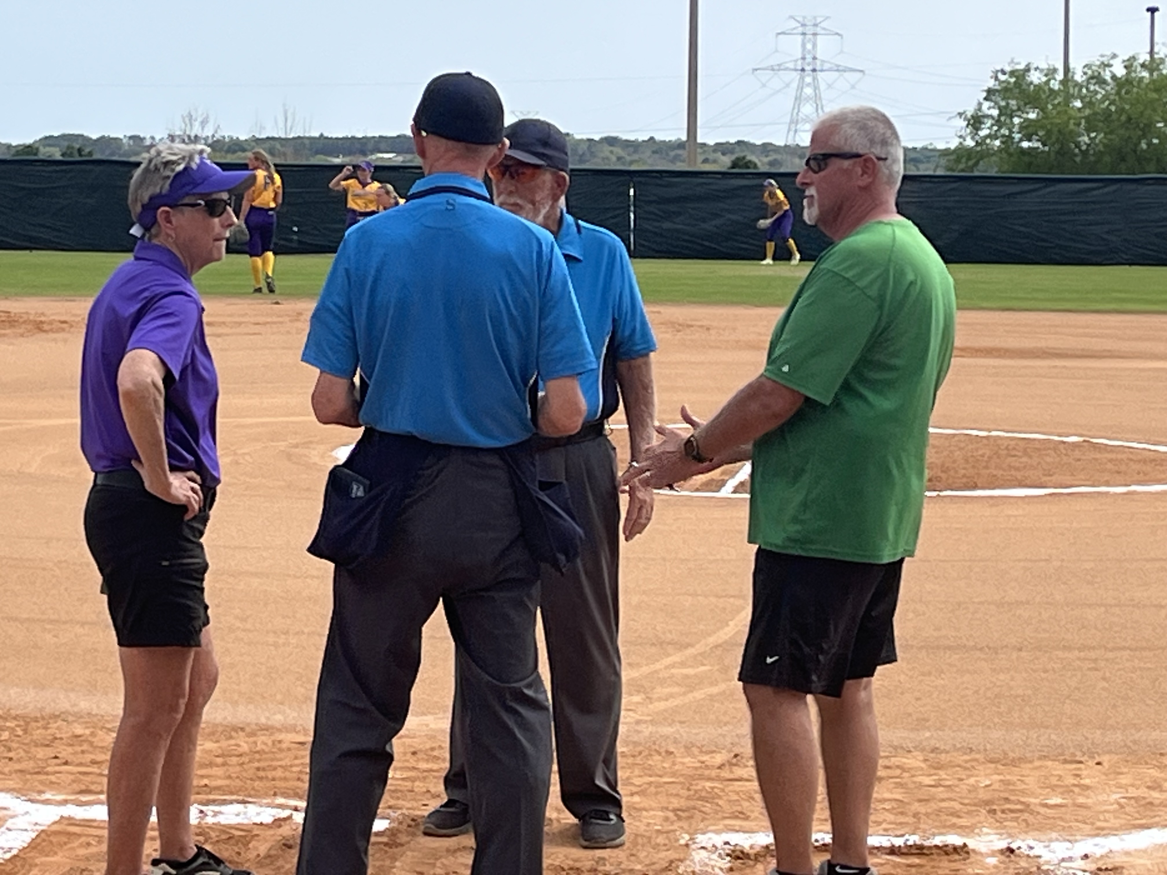 Minnesota State - Mankato head coach Lori Meyers (left) meets with the opposing coach and umpires before a Saturday game at THE Spring Games