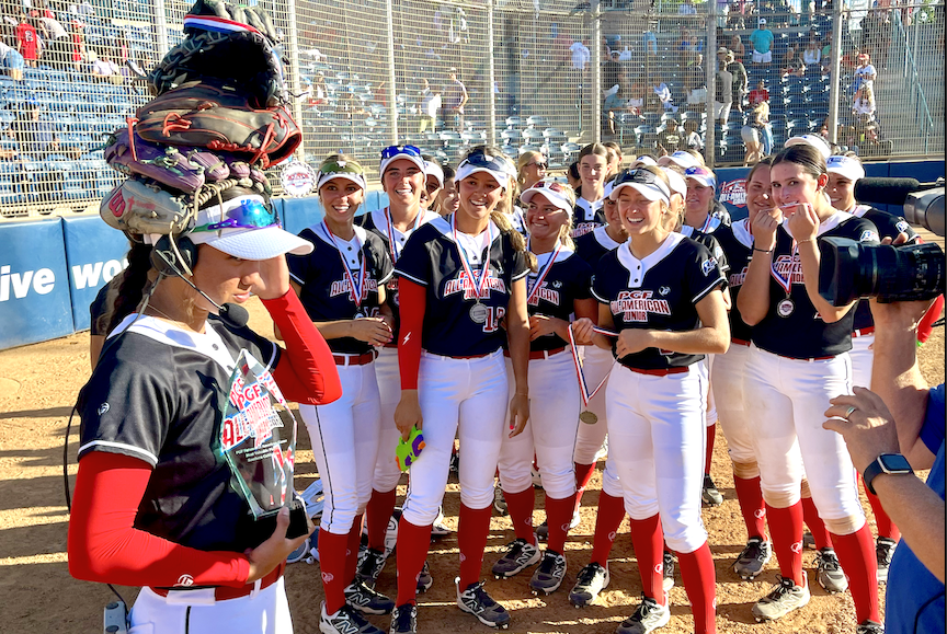 Milan Torres (left) does a live TV interview after her Juniors All-American teammates placed several gloves on her head!